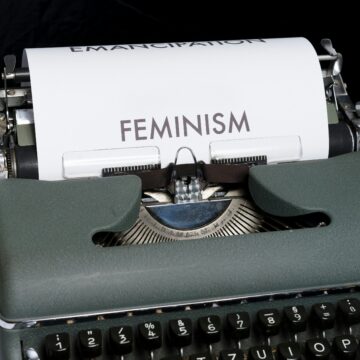 a vintage typewriter with the word "feminism" typed onto white paper