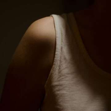 a shadowy photo of a girl wearing a cream colored tank top