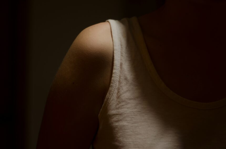 a shadowy photo of a girl wearing a cream colored tank top