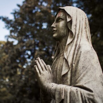 A statue of the virgin mary in a cemetery