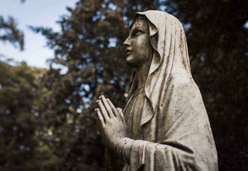 A statue of the virgin mary in a cemetery