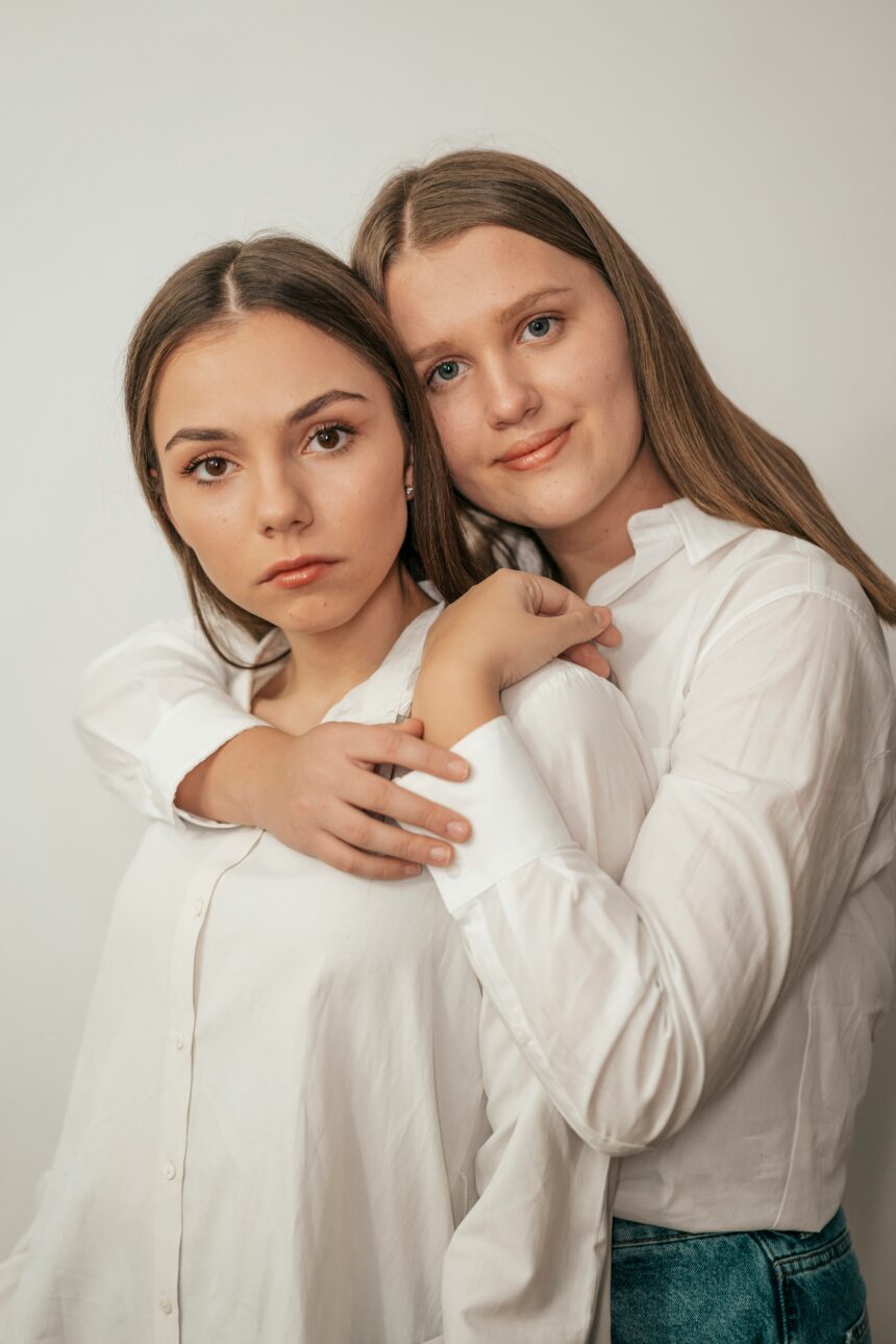 teslariu-mihai-N675cWFXAl8-unsplash A photo of two women posing in a hugging position in a gallery. The background is white, shirts are white, and they're both wearing jeans